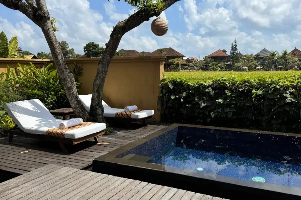 A private pool area featuring lounge chairs and a lush garden backdrop in Ubud, Bali.