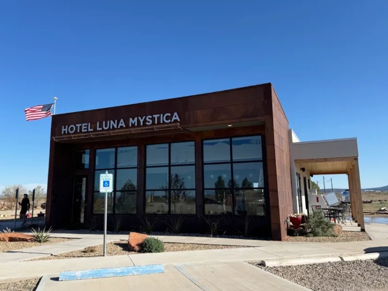 Front view of Hotel Luna Mystica reception with a clear blue sky in the background and an American flag waving.