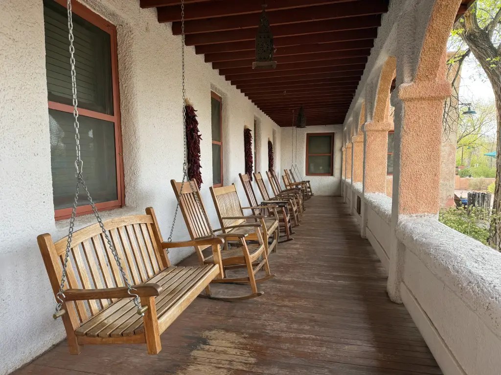 A porch with wooden rocking chairs and a serene atmosphere, adorned with a rustic white wall and earthy decor.