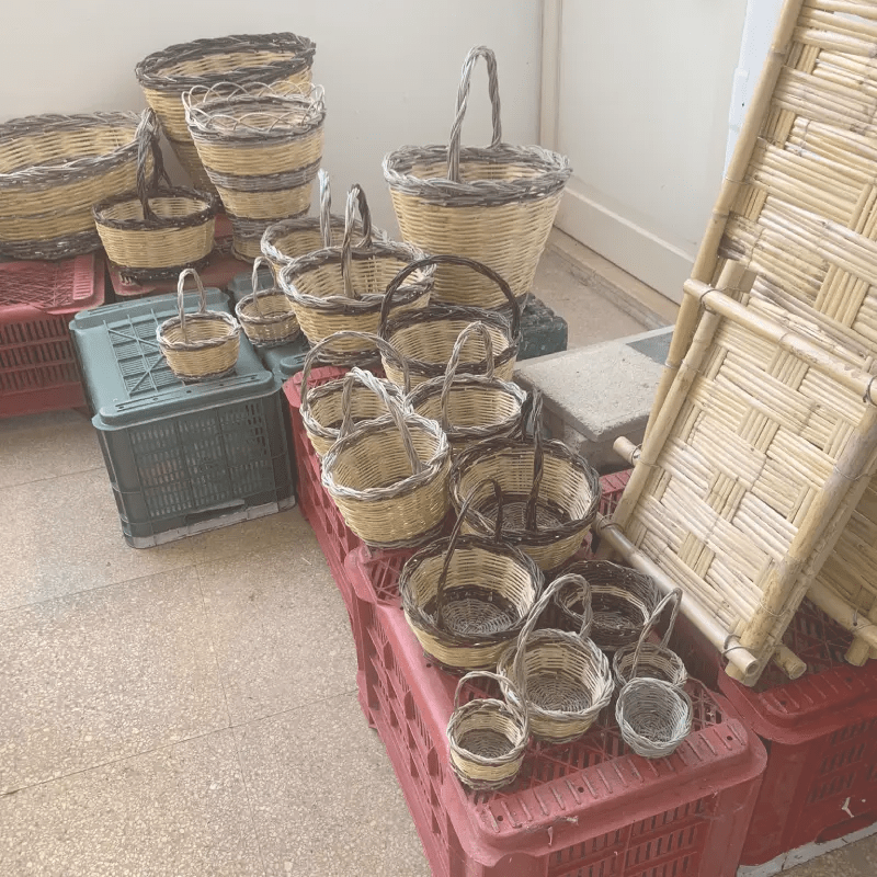 A collection of handmade woven baskets of various sizes, displayed on red crates in a studio setting.