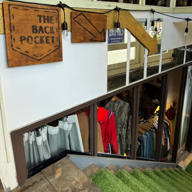 Entrance to The Back Pocket boutique featuring wooden signs and a staircase leading down to the store.