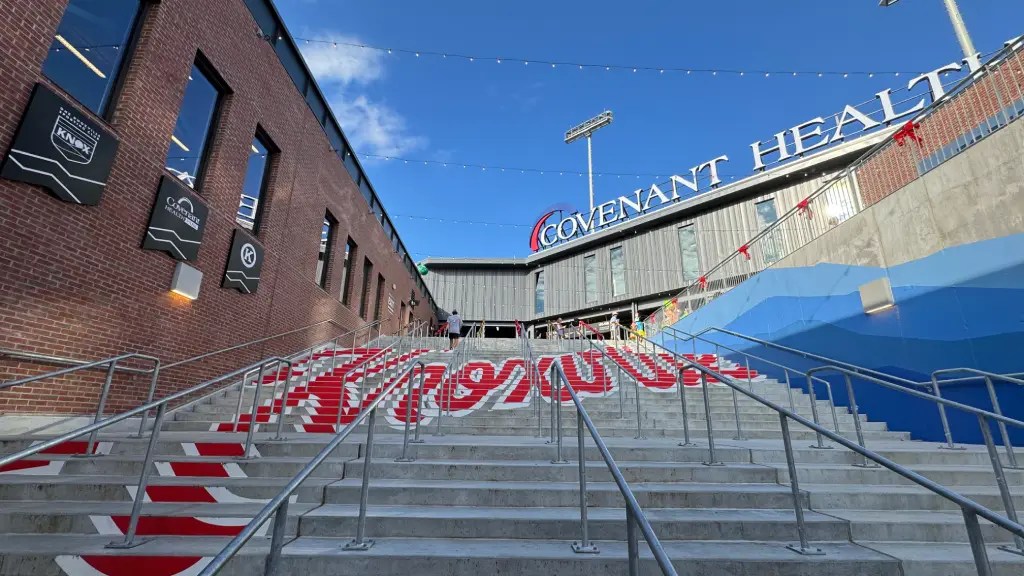 Staircase leading up to Covenant Health Park, with signage and festive decorations visible against a clear blue sky.