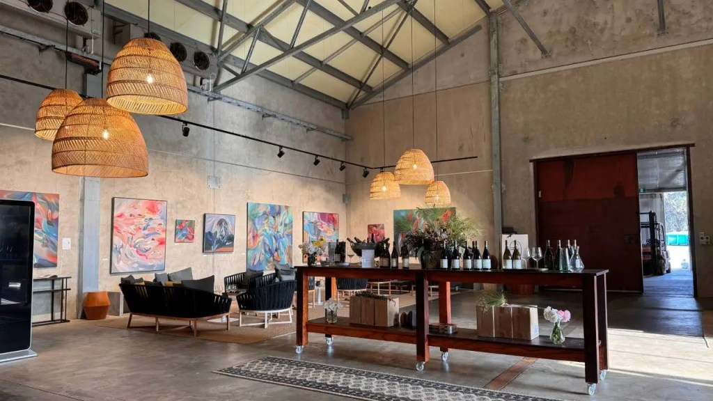 Stylish interior of a winery tasting room featuring modern art on the walls, comfortable seating, and decorative pendant lights.