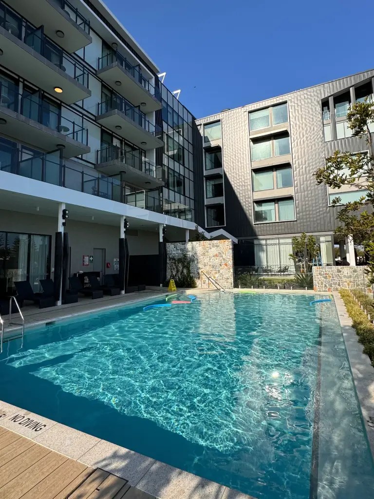 Swimming pool view at Hilton Garden Inn Busselton, featuring modern architecture and lush greenery.