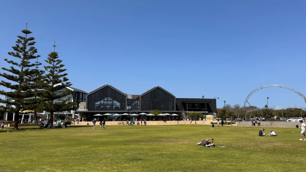 Outdoor view of Shelter Brewing Co. in Busselton, with modern architecture, trees, and people enjoying the grassy area.