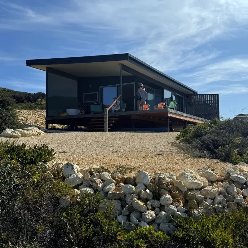 A modern coastal home in Bremer Bay, Australia, featuring a large deck and scenic surroundings with a person standing on the porch.