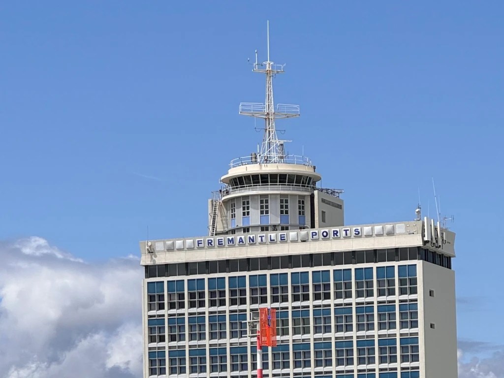 A close-up view of the Fremantle Ports building under a clear blue sky, showcasing its architecture and signage.