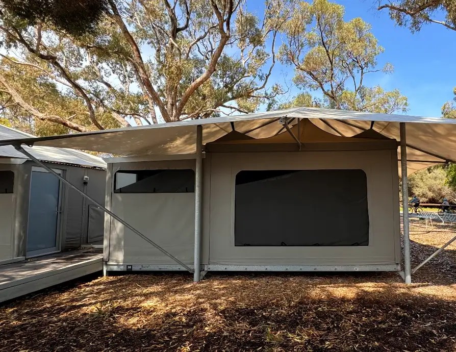 Exterior view of a Superior Tent at Discovery Resorts on Rottnest Island, surrounded by trees and outdoor seating.